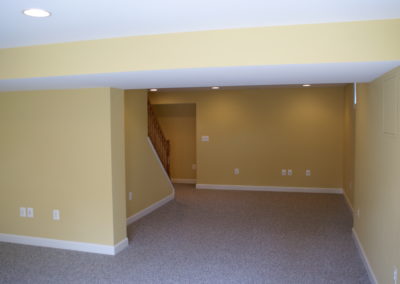 Open basement, gray carpet, yellow walls.