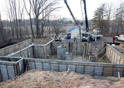 Home being built, exterior. Metal/concrete foundation, work crew and crain.