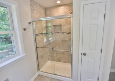 Master Bathroom view 1- Glass door shower, stone tiled walls in shower, white walls outside